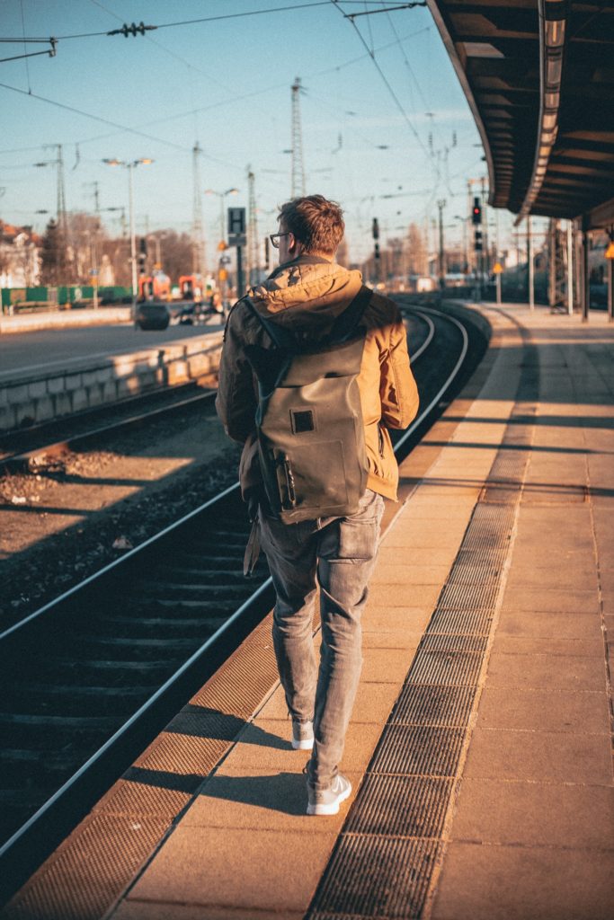 Man standing on train platform with blue skies