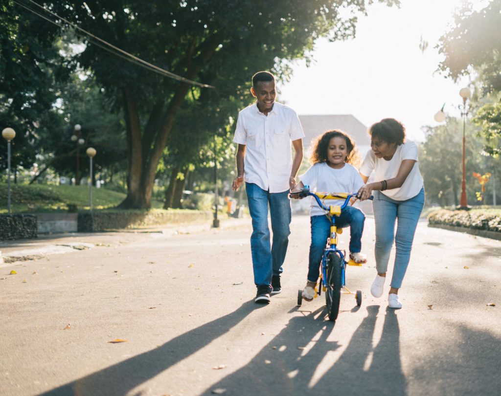parents showing child how to ride a bike