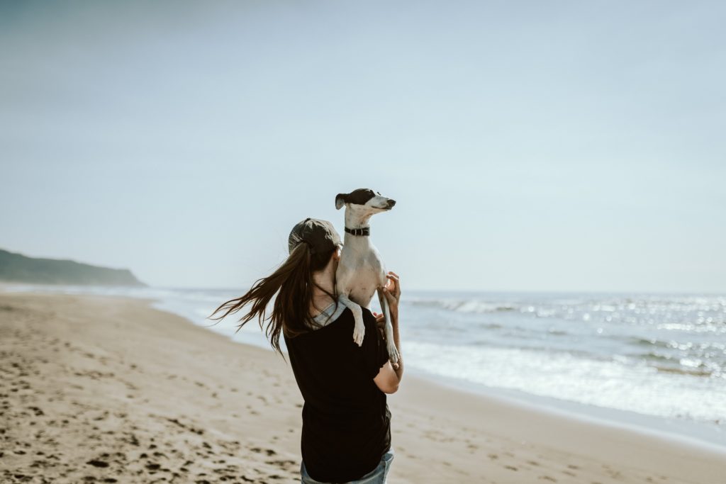 woman holding dog on a beach