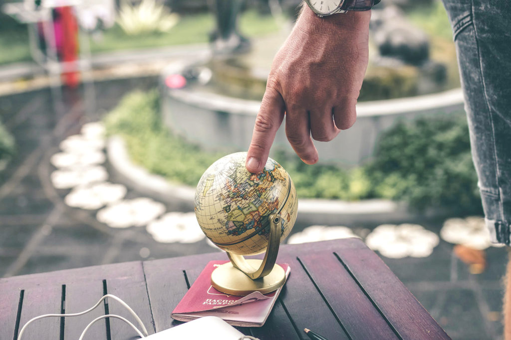 Hand pointing on a tiny globe outside on a table