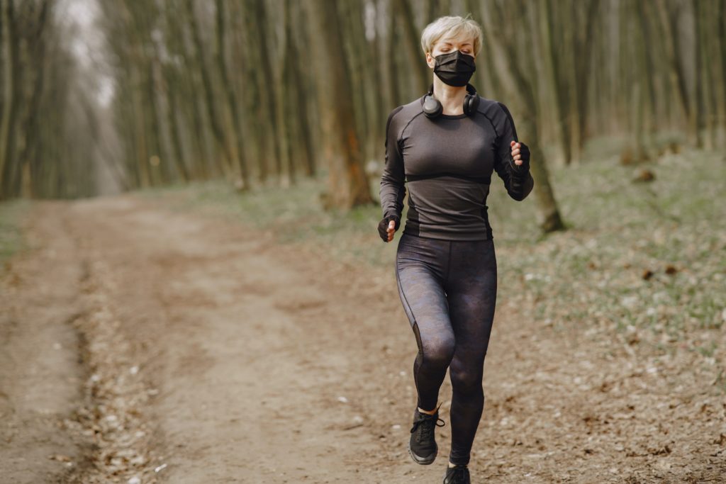Female runner outside on trails wearing mask