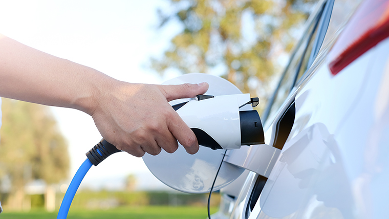 Close up view of someone plugging charger into electric vehicle