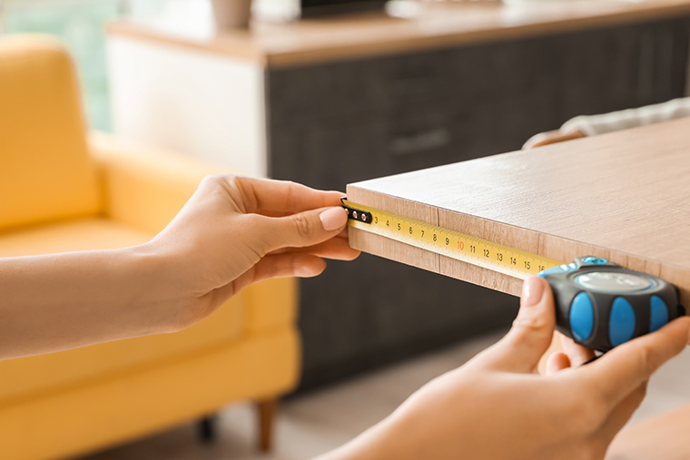 Woman using tape measure to measure table in her perfect NJ apartment