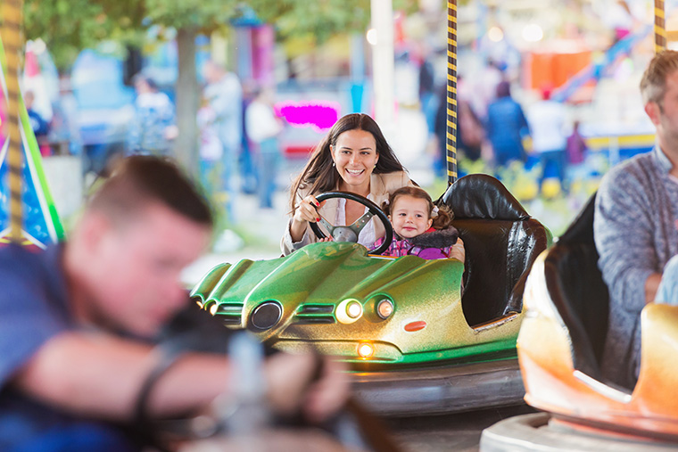 Mother and young daughter smiling on bumper car