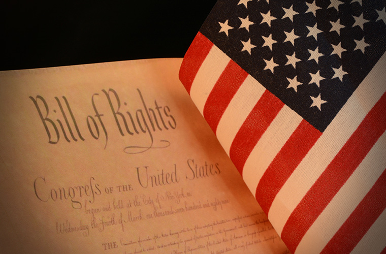 Artistic depiction of the Bill of Rights with American Flag next to it. 