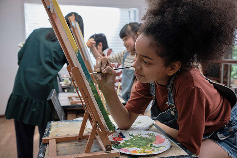 A youthful girl enjoying painting on a canvas during an art class