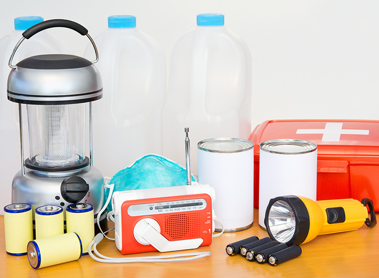 Emergency kit with lattern, flashlight, batteries, walkman, canned foods, first aid kit and gallon water jugs.